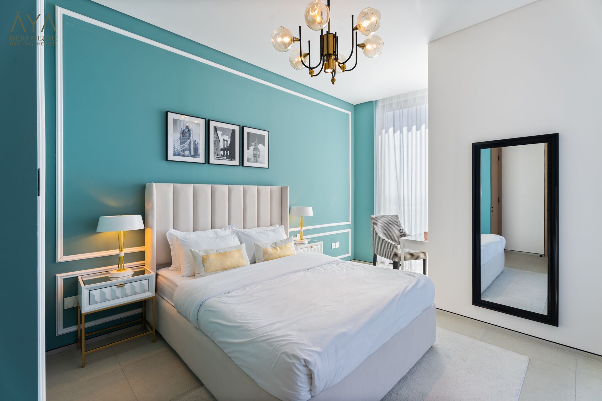 Une chambre à coucher moderne avec un grand lit, deux tables de chevet avec des lampes, un lustre et un grand miroir.