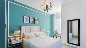 Un dormitorio moderno con una cama grande, dos mesitas de noche con lámparas, un candelabro y un espejo amplio.