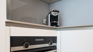 Una cocina moderna con horno empotrado y cafetera sobre la encimera.