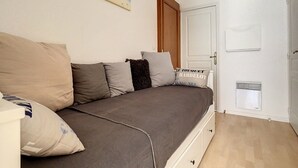 A bedroom with a bed, a wooden door, a white wall, and a painting of sailboats. - Bright Apartment Near Beach with Parking, Balcony & Modern Amenities – Stella (Cucq-Stella Plage)