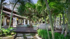 Un complexe hôtelier tropical doté d’une piscine, d’une terrasse en bois et d’une végétation luxuriante.
