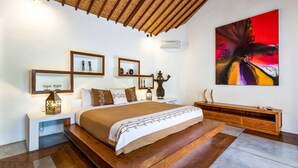 Une chambre à coucher moderne avec un grand lit, une tête de lit en bois, des tables de chevet avec des lampes, une console en bois et un grand tableau abstrait accroché au mur.