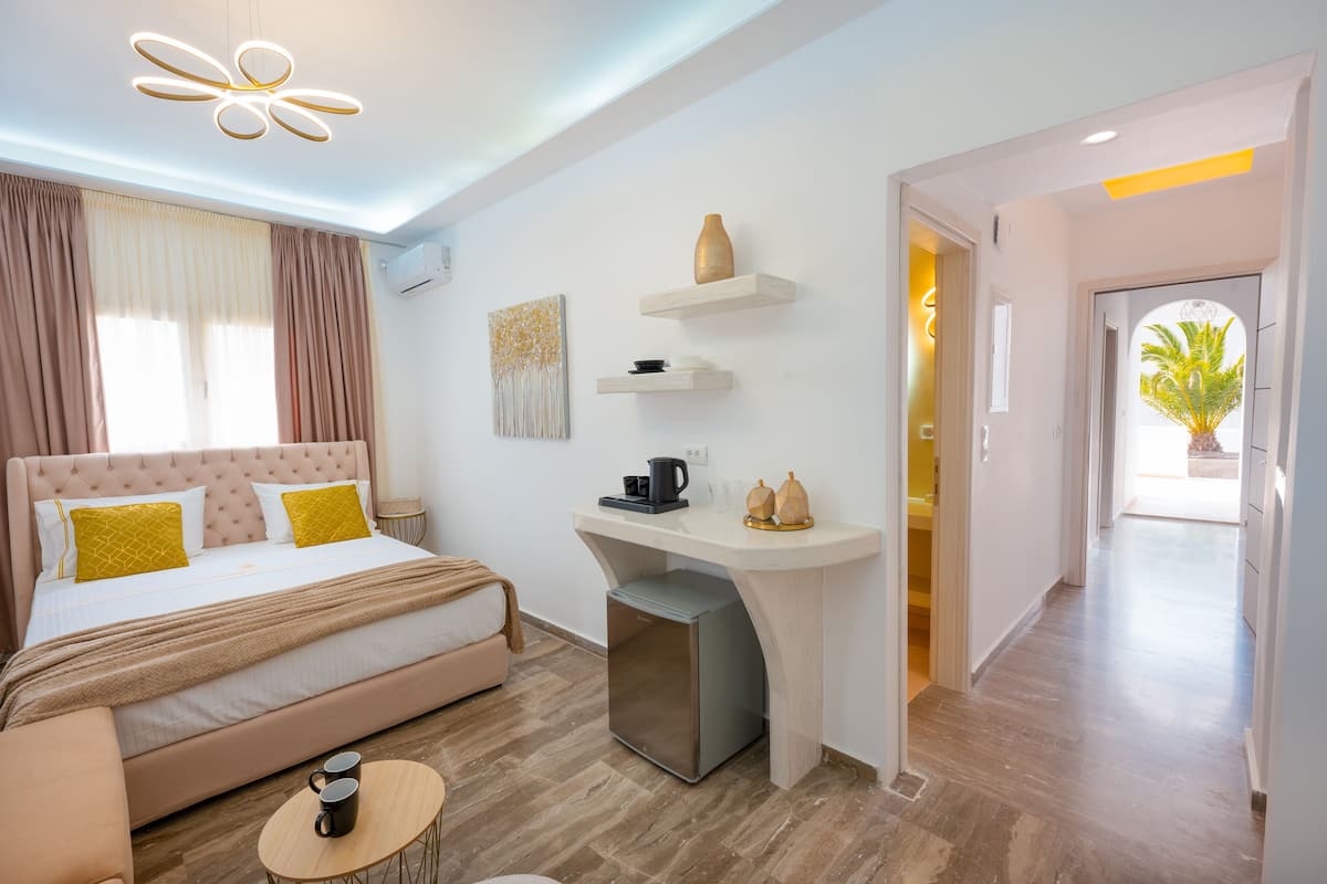 Ein modernes Hotelzimmer mit Bett, Nachttisch und Schreibtisch mit Kühlschrank.