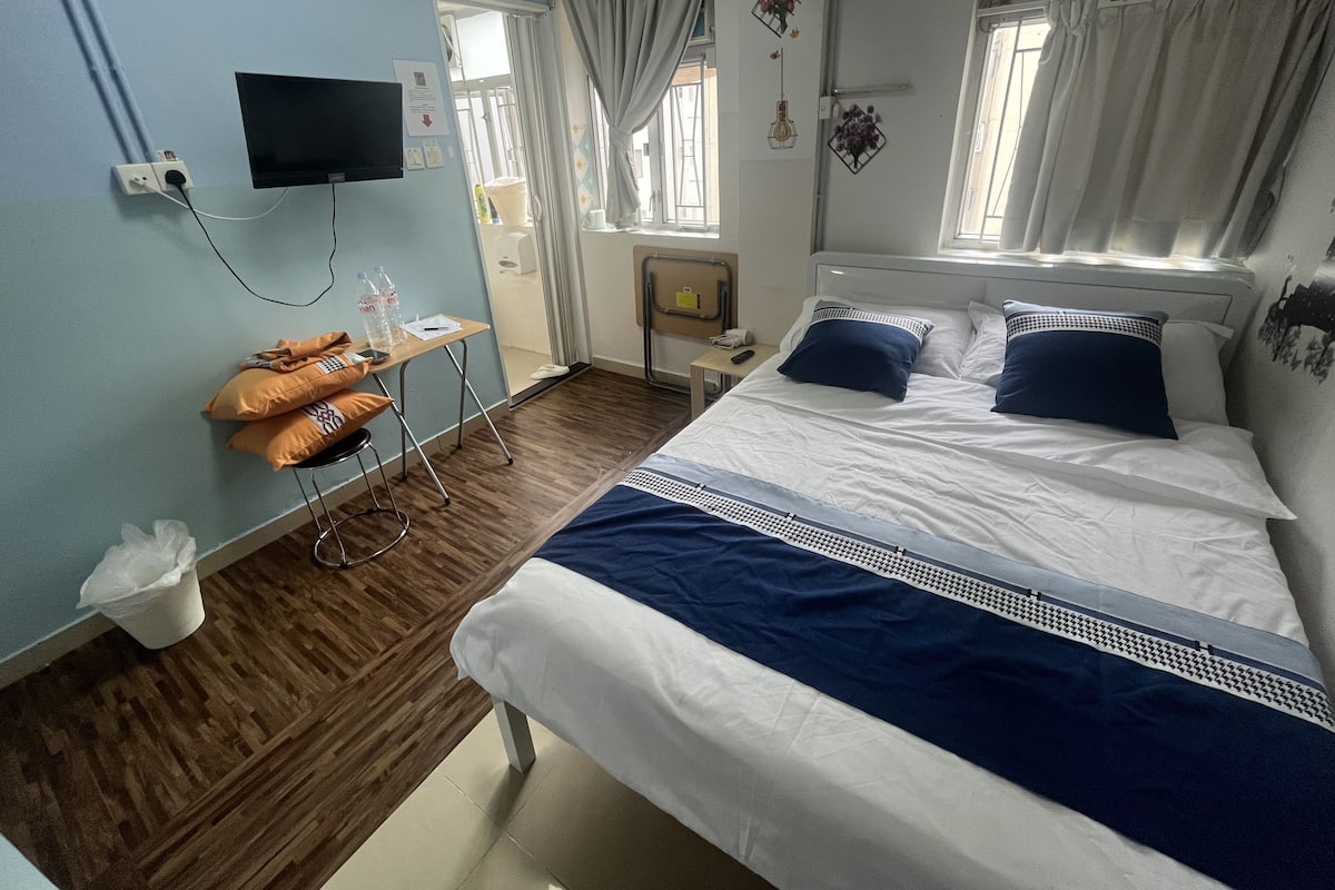A hotel room with a bed, a desk, a chair, a television, and a window with curtains.