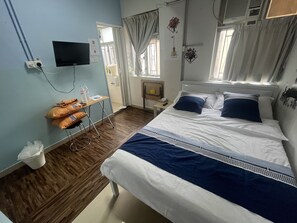 A hotel room with a bed, a desk, a chair, a television, and a window with curtains. - Guesthouse Inciti (Kowloon)