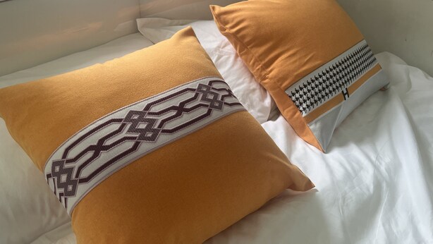 A bed with two pillows, one with a geometric pattern and the other plain. - Guesthouse Inciti (Kowloon)