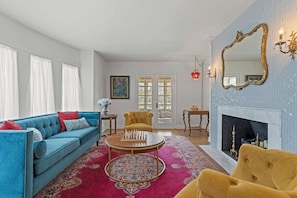 A living room with a blue sofa, yellow armchair, and a fireplace. - Beautiful Villa Leocadia+ Private Pool + Sleeps 8! (Kansas City)