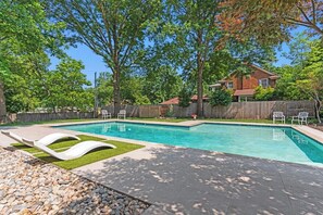 Une piscine dotée d’une terrasse en bois, entourée d’arbres et d’une clôture en bois.