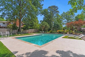 A rectangular swimming pool with a tiled deck surrounding it, a grassy area, and a wooden fence in the background. - Beautiful Villa Leocadia+ Private Pool + Sleeps 8! (Kansas City)
