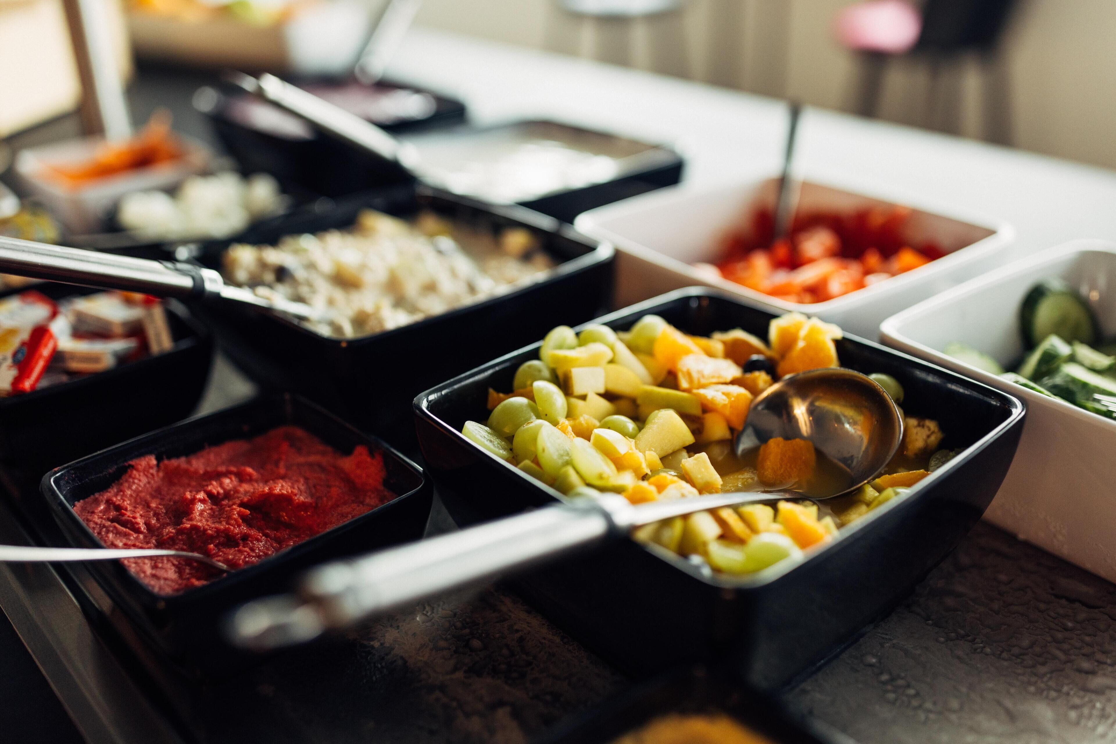 A buffet with various food items in black and white trays.