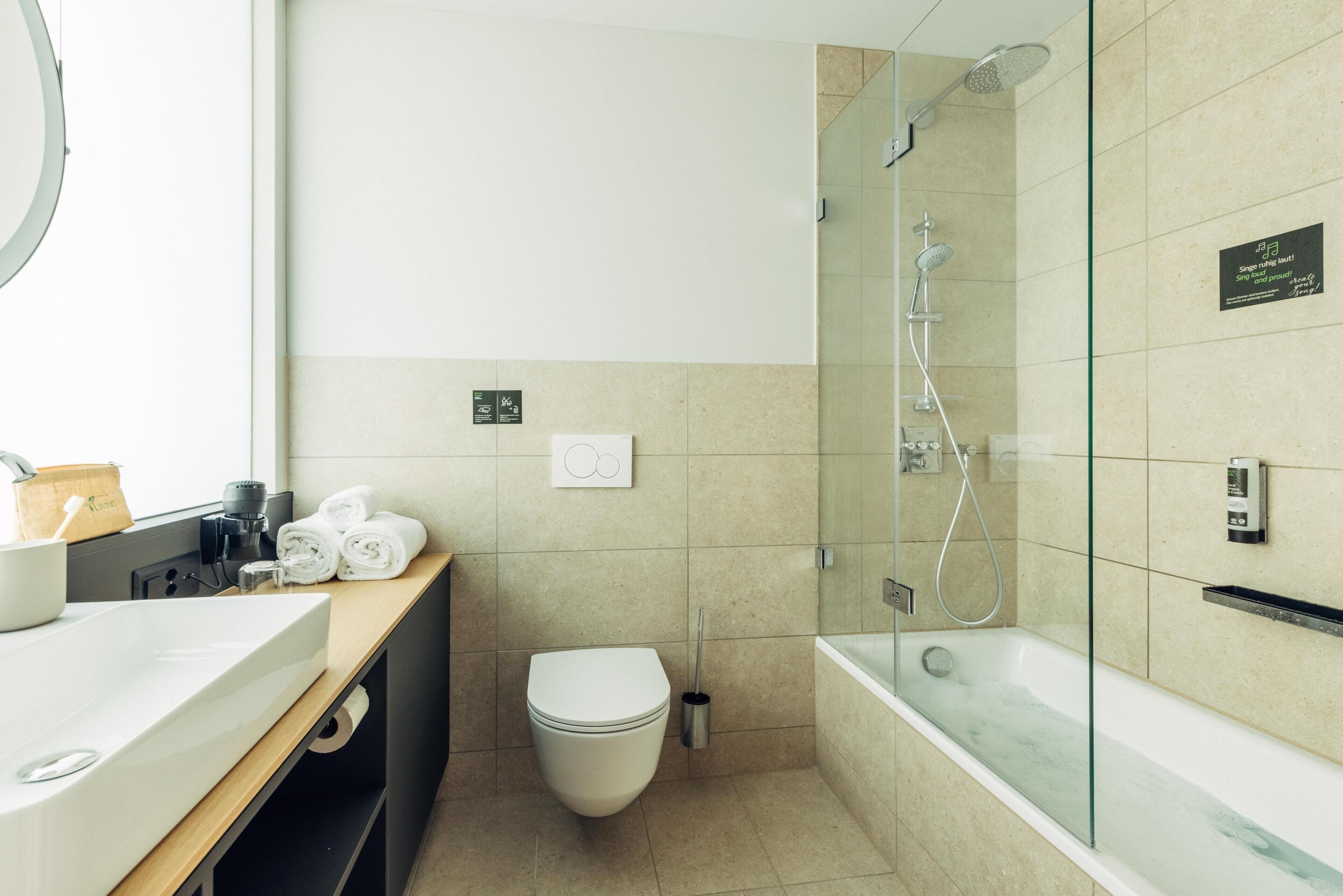 Un baño moderno con lavabo, inodoro y ducha con mampara de vidrio.