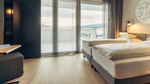 Una habitación de hotel con un ventanal grande, una cama, un escritorio y una silla.