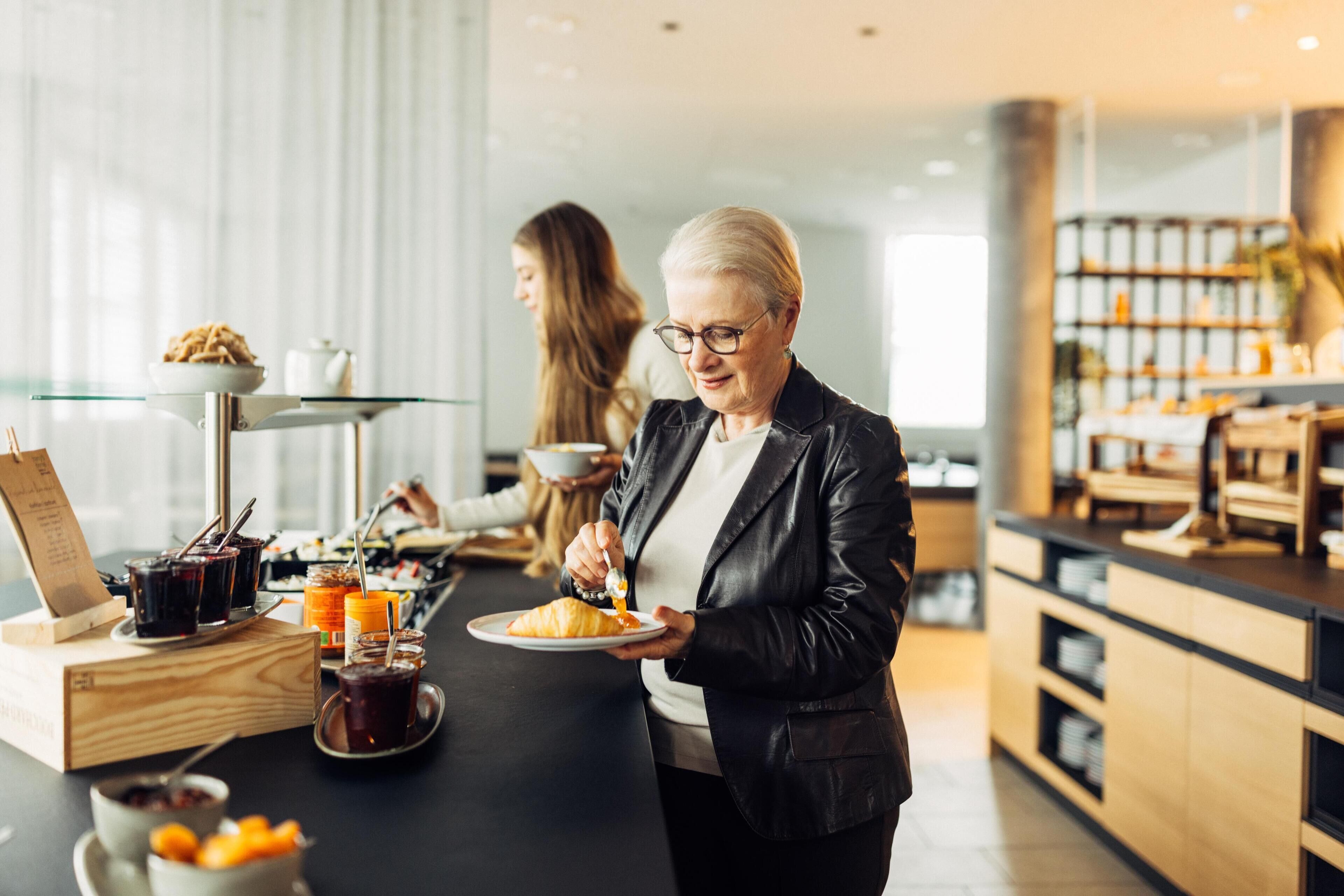 A breakfast setting with a tray of croissants and beverages, a wooden box, and a glass table.