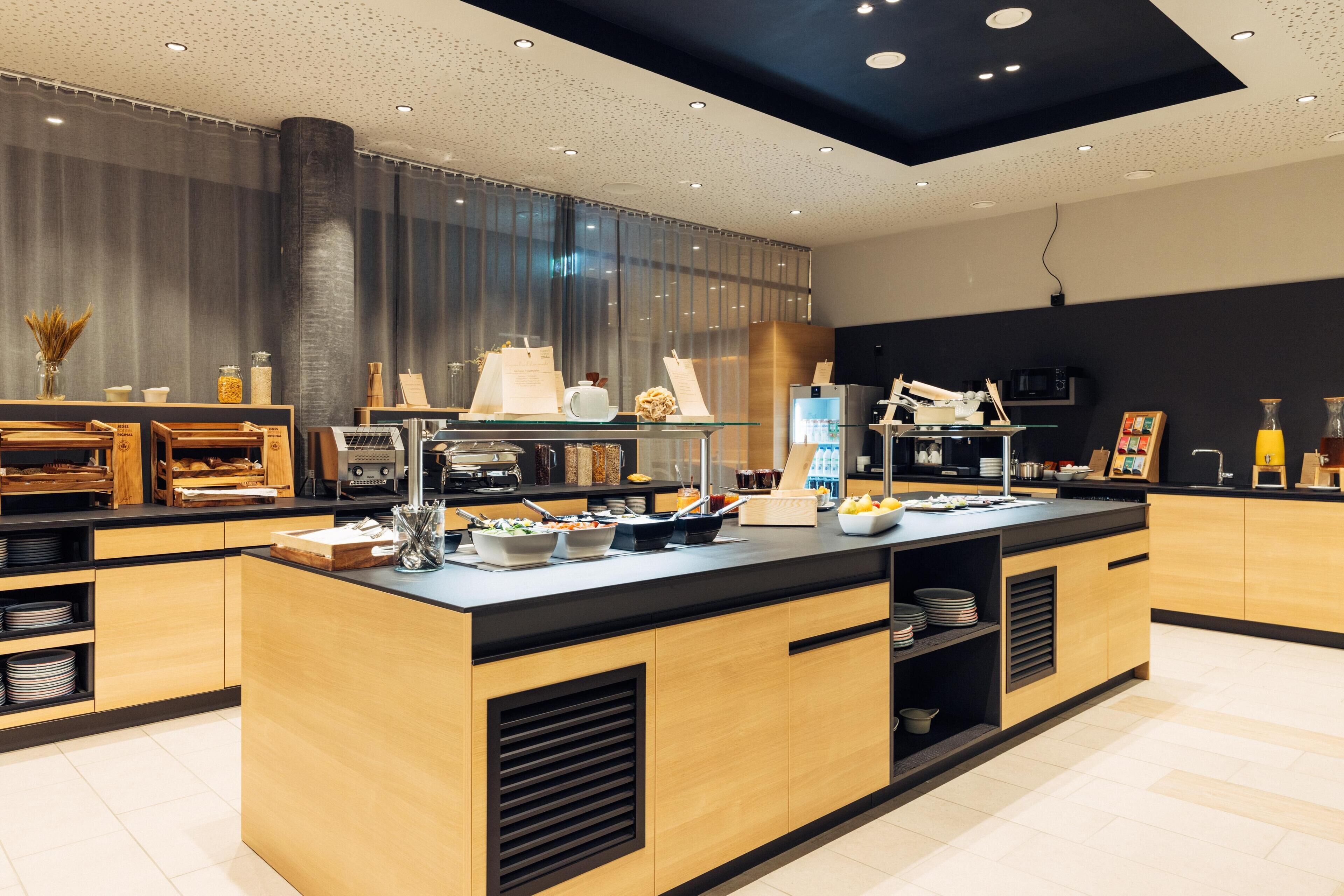 Una cocina moderna con una isla central, armarios de madera y encimera negra.