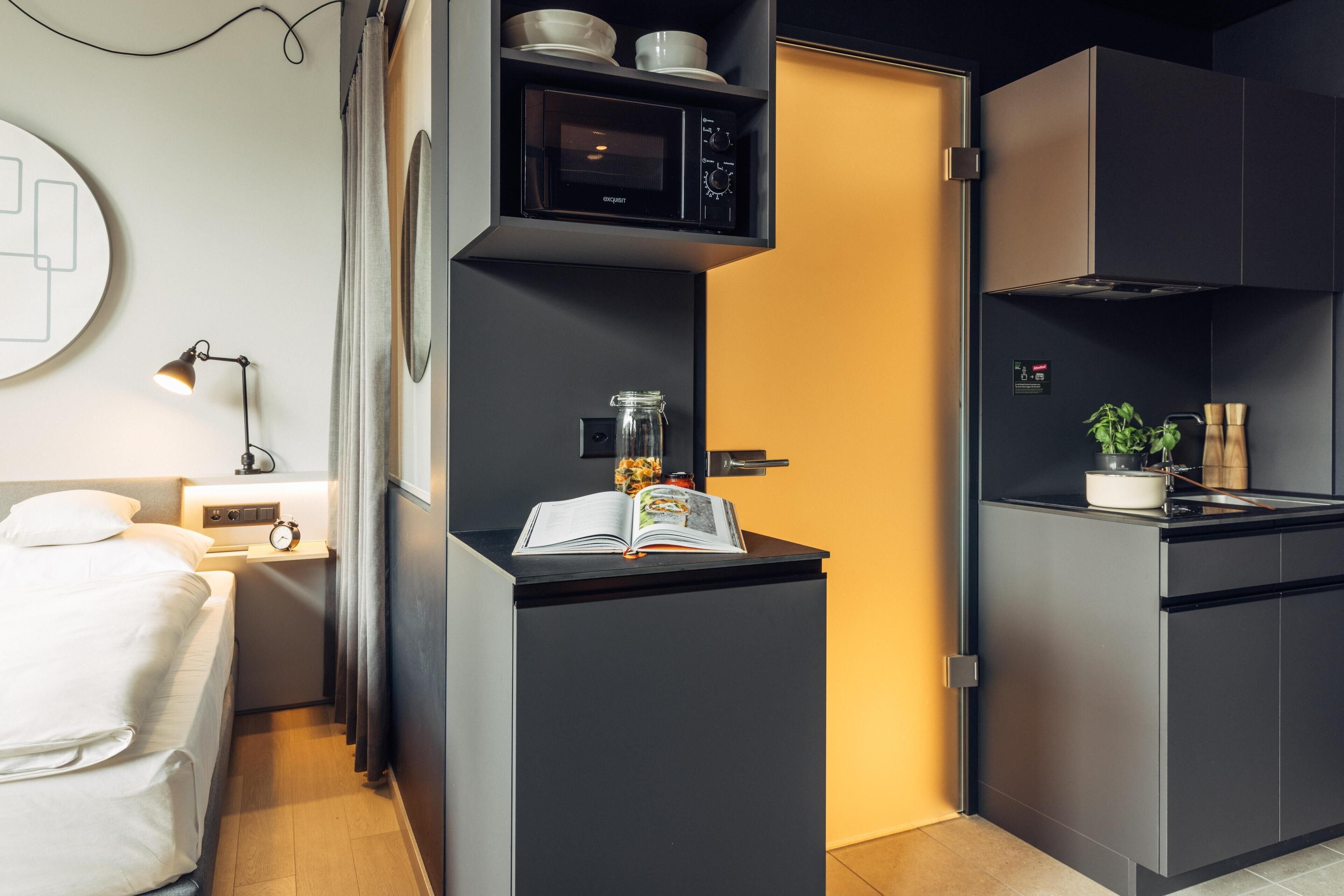 Una kitchenette compacta con microondas, un refrigerador pequeño y una cafetera.