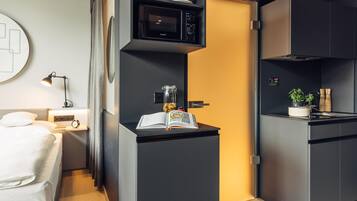 Una kitchenette compacta con microondas, un refrigerador pequeño y una cafetera.