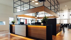 Un área de bar moderna con mostrador de madera, asientos y ventanas amplias.