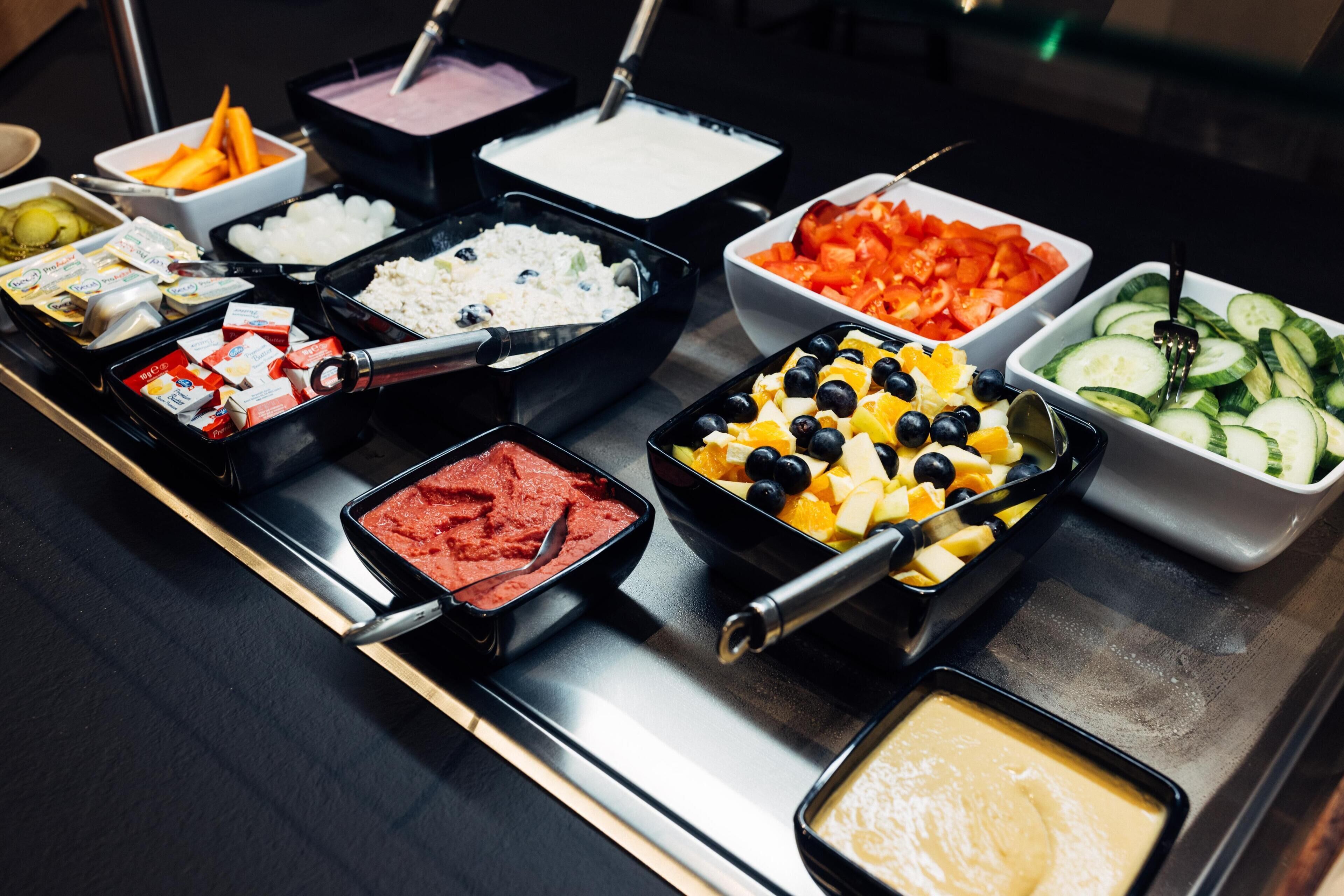 Un buffet proposant une variété de plats, notamment des fruits, des légumes et des sauces.