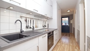Une cuisine moderne avec des meubles blancs, un évier noir et un plancher en bois.