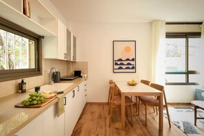 Una cocina moderna con comedor, suelo de madera y vistas al exterior.