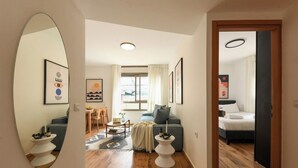 A modern living room with a sofa, a dining area with a table and chairs, and a bedroom with a bed. - Mamad Relaxed Beachside Living | Cozy 2BR (Tel Aviv-Yafo)