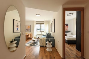 A modern living room with a sofa, a dining area with a table and chairs, and a bedroom with a bed.