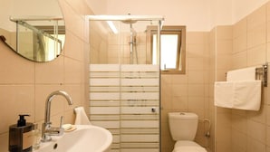 A bathroom with a glass shower enclosure, a sink with a faucet, a toilet, and a towel rack. - Mamad Relaxed Beachside Living | Cozy 2BR (Tel Aviv-Yafo)