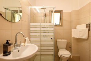 A bathroom with a glass shower enclosure, a sink with a faucet, a toilet, and a towel rack.