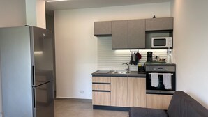 A compact kitchen with a built-in microwave, a stainless steel refrigerator, and wooden cabinets. - the garden of Etna (Mascalucia)
