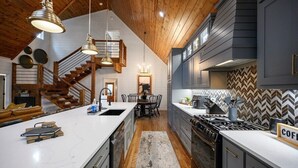 Een moderne keuken met een groot eiland, een houten plafond en een backsplash van visgraatmozaïek.