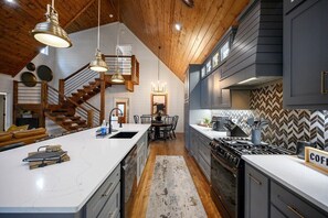 Enjoy cooking in this well-equipped kitchen with a central island, sink, and stove, plus a hinged staircase to the upper level.