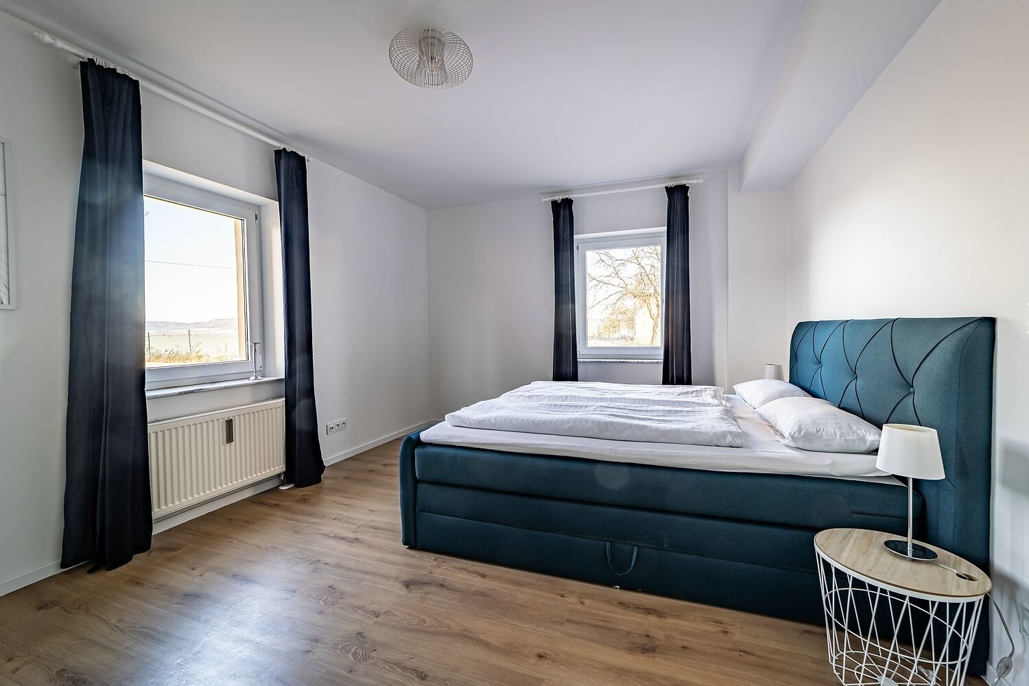 Une chambre à coucher avec un lit, une fenêtre, un radiateur et une lampe.