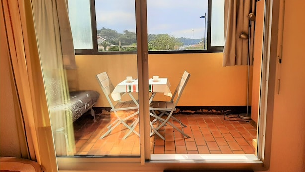 A room with a sliding glass door leading to an outdoor area with a table and chairs, a sofa, and a view of a hilly landscape. - Ideal studio near beach and port, sleeps 3 (Capbreton)