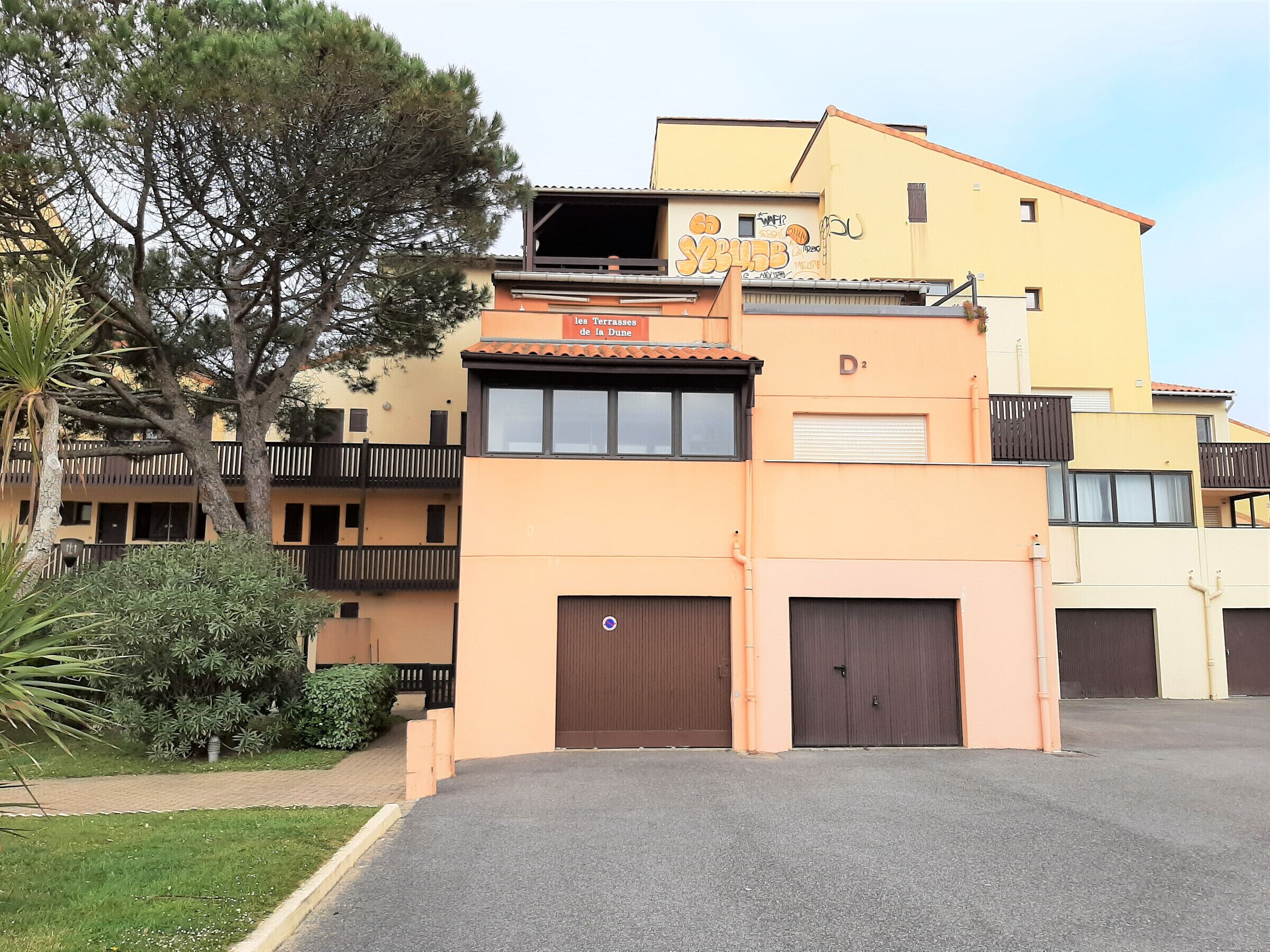 Un edificio de varios pisos con techo plano, balcones y entrada protegida por una reja.