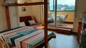 A room with a bed, a table, a sofa, and a balcony with a table and chairs. - Ideal studio near beach and port, sleeps 3 (Capbreton)