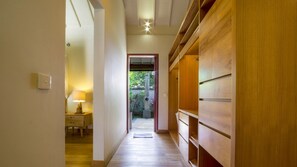 Un couloir avec une armoire en bois, une table de chevet avec une lampe et une vue sur un jardin extérieur.