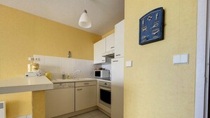 Une cuisine compacte équipée d’un four à micro-ondes, d’un four traditionnel et d’une machine à café, le tout installé sur le plan de travail.