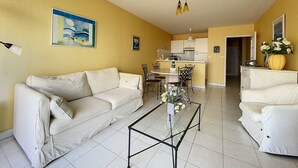 Un salon comprenant un canapé, une table basse et un coin repas avec des chaises et une table.