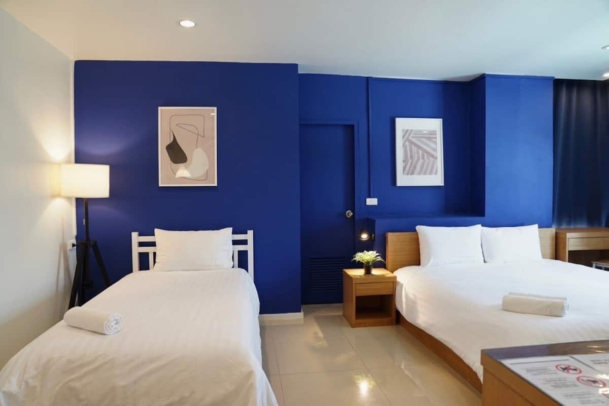 A hotel room with two beds, a nightstand with a lamp, and artwork on the walls.