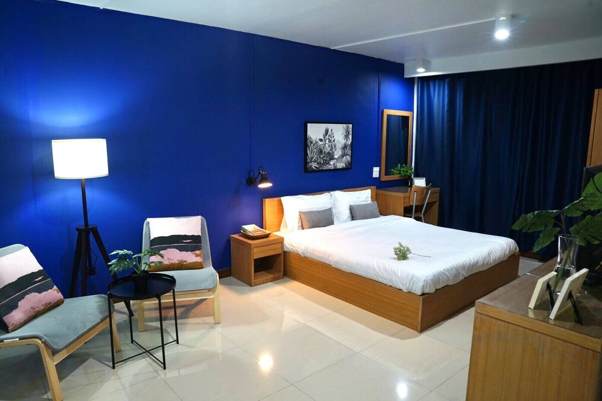 A modern bedroom with a large bed, bedside tables, a desk, and a chair.