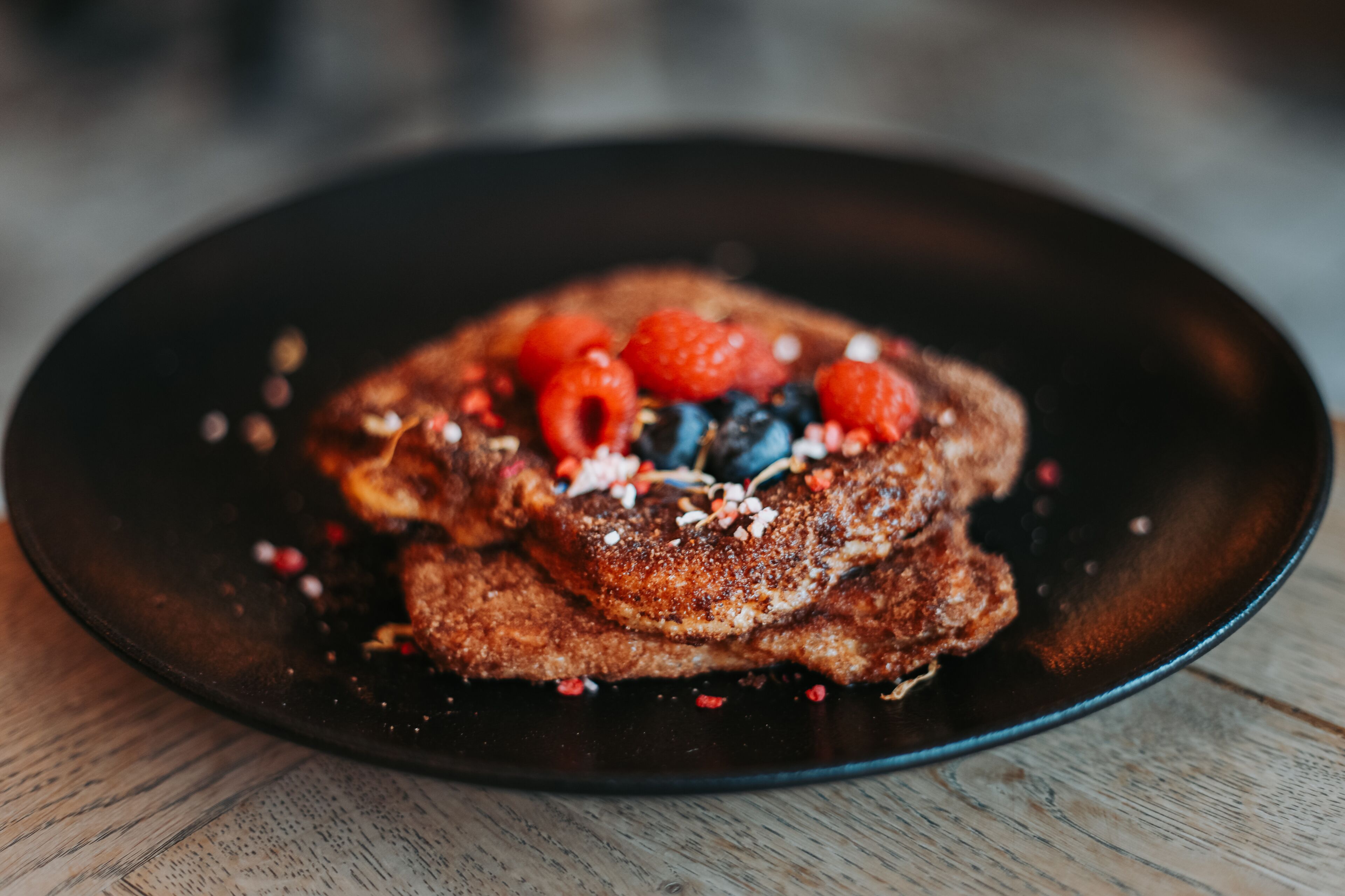 Ein Teller Französisch Toast mit Beeren und bestreut mit Zucker.