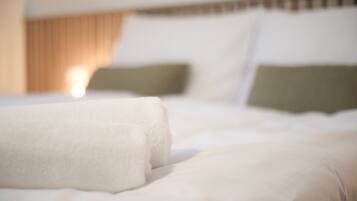 A bed with white linens and two pillows, one green and one white, in a hotel room.