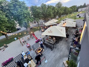 Un espace extérieur aménagé avec des tables et des chaises pour prendre les repas, une aire de jeux pour enfants et un stand de restauration.