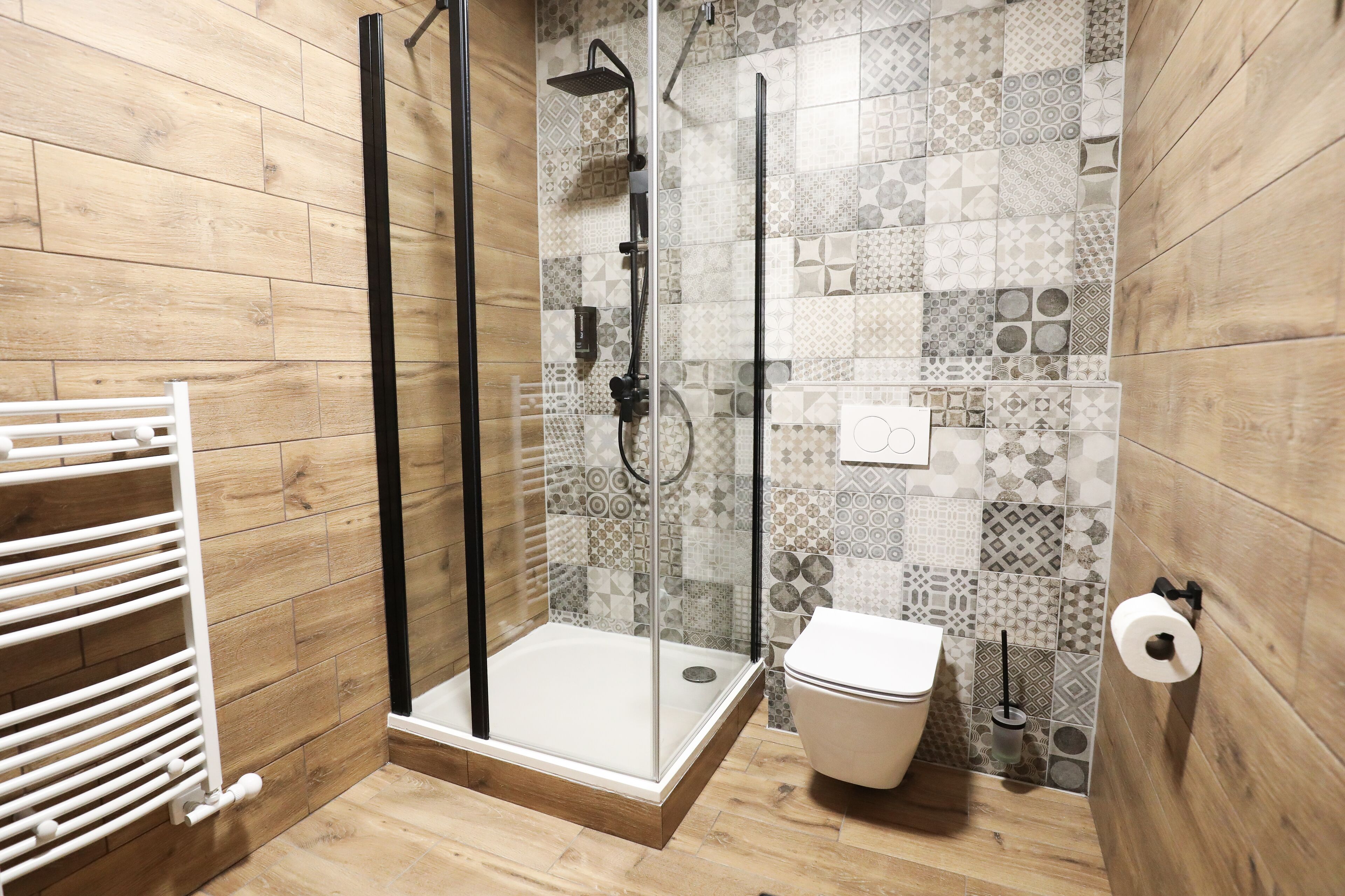 A modern bathroom with a shower, toilet, and a towel rack.