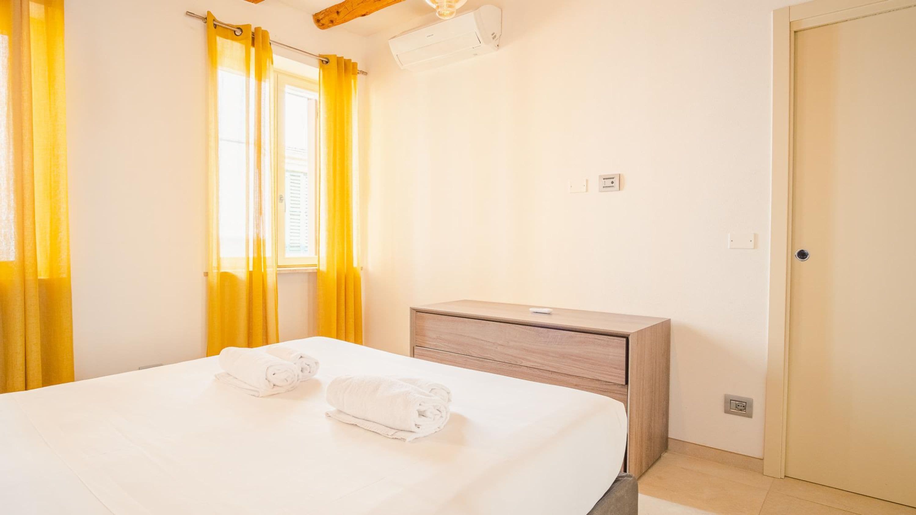 A hotel room with a bed, a wooden nightstand, and a door.