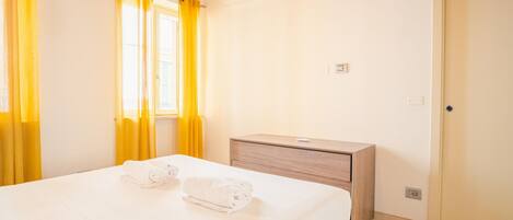 A hotel room with a bed, a wooden nightstand, and a door.