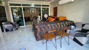 A modern dining area with a long table, chairs, and a ceiling fan. - Studio'Z (Chiang Mai)