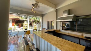A modern kitchen with a wooden counter, a built-in oven, and a large window overlooking a street. - Studio'Z (Chiang Mai)