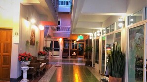 A hotel lobby with a central seating area, a staircase, and a glass storefront. - Studio'Z (Chiang Mai)