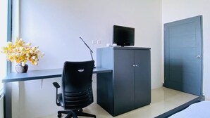 Una habitación moderna con escritorio, silla, televisión y armario.